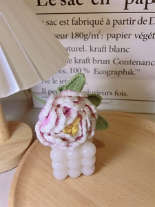 Detailed close-up of handmade crochet peony flower resting on a white bubble candle base