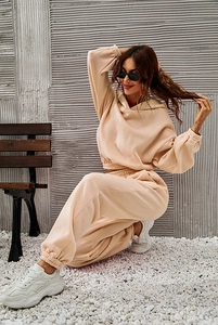 Detail of apricot hooded tracksuit featuring drop shoulder and elastic cuffs on hoodie