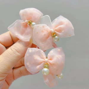 Detailed view of pink polka dot mesh hair ties with pearl charms and gold metal rings