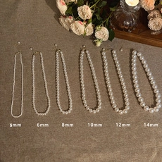 Comparison of pearl sizes from 5mm to 14mm for choker necklaces on vintage fabric background