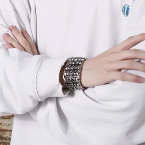 Close-up of a wide punk rock skull bracelet in vintage silver finish on a male wrist