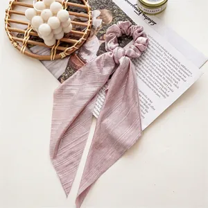 Close-up of pink silk satin scrunchie with long ribbons on a decorative setting