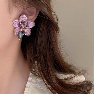 Gros plan détaillé de boucles d'oreilles fleurs brodées violettes avec perles de cristal