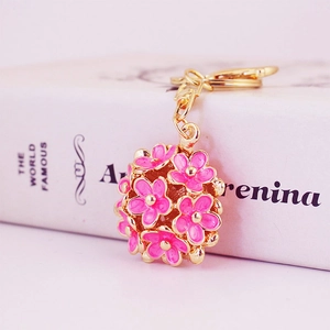 Pink and gold 3D hollow flower keychain pendant on a book, stylish bag accessory charm