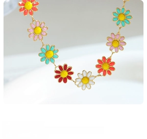 Macro shot of colorful enamel daisy charms necklace with gold-plated metal link chain