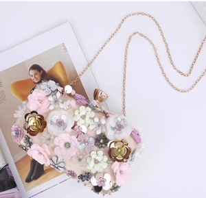Close-up of evening clutch bag featuring 3D floral petals and golden chain detail