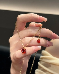 Close-up of golden necklace featuring two ruby red heart-shaped zircon crystal pendants
