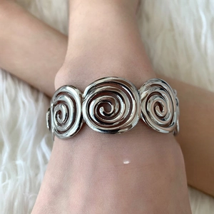 Close-up of a silver vintage spiral cuff bracelet with triple swirl metallic texture