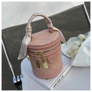 Detail of pink cylinder bucket bag with silk scarf handle and gold hardware zipper