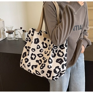 Grand sac cabas en toile à motif léopard porté à l'épaule par un mannequin de mode
