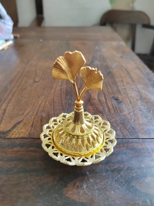 Top view of golden incense burner with ginkgo leaf design and hollow base details