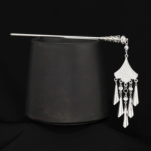 Detailed view of silver ethnic hair pin with long tassel pendants on ceramic base
