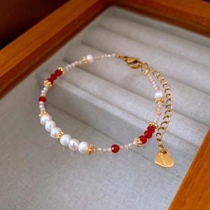 Détail du bracelet perles avec cristaux rouges et breloque coeur doré sur velours gris