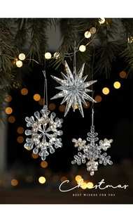 Detail of crystal acrylic snowflake and star ornaments hanging on a Christmas tree branch