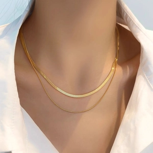 Close-up of double-layered gold snake chain necklace with flat and fine link textures