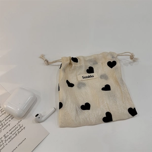 Detail of beige corduroy drawstring pouch featuring black heart patterns for storage