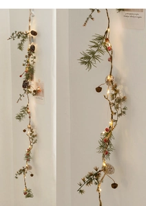 Detail of Christmas garland with pine cones, red berries, bells and warm LED lights