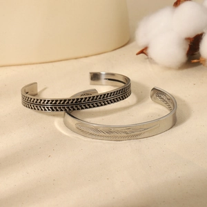 Set of two vintage silver open cuffs featuring feather texture and geometric braid patterns