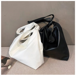 Detail of minimalist black and white tote bags with wide knotted shoulder straps