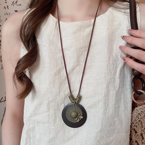 Detail view of retro wooden round pendant with vintage bronze hat and brown leather cord