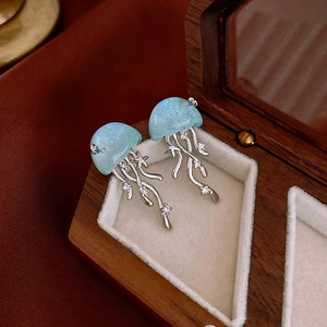 Macro de boucles d'oreilles méduses bleues avec glands argentés et détails d'étoiles