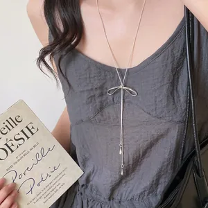 Detail of silver bowknot y-shaped lariat necklace with fringe and teardrop pendants