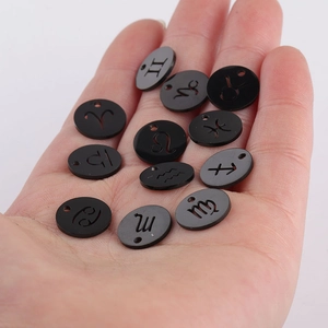 Detailed close-up of twelve black round zodiac charms in mirror-finish titanium steel