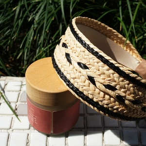 Detailed close-up of woven raffia headband with natural texture and black stripes