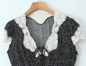 Close-up of black polka dot dress featuring a white lace collar and decorative bow tie