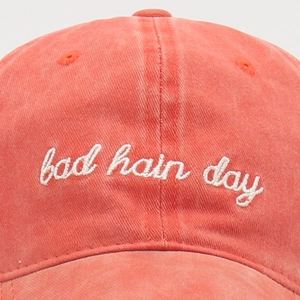 Macro detail of the bad hair day white embroidery on the coral red washed cotton cap
