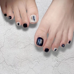 Close-up of toenail press-ons featuring an abstract brushstroke design in black and white