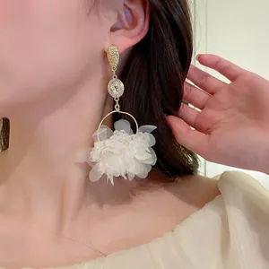 Detail of elegant white mesh flower drop earring with gold finish and zircon accents