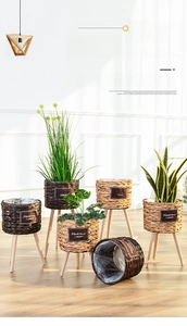 Detail of woven straw plant pots with wooden legs and protective plastic lining