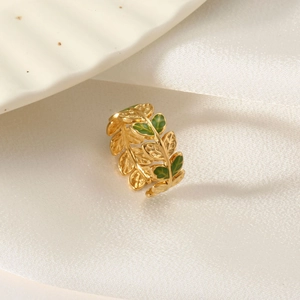 Detail view of golden olive leaf ring with green enamel finish on white silk background