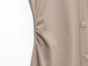 Detalle de tejido de punto acanalado y botones dorados de un vestido camisero caqui