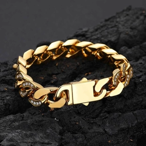 Detail of 12mm gold cuban link bracelet with inlaid zircon crystals on a dark stone