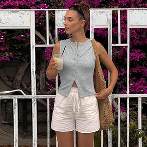Détail du gilet en maille grise avec boutons et short blanc à cordon de serrage