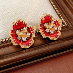 Detailed close-up of vintage enamel flower earrings with red petals and crystal center