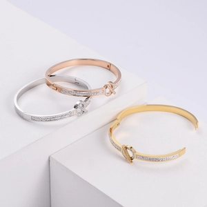 Close-up of three metallic bangle bracelets with crystals on white geometric steps