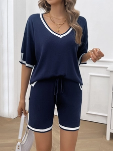 Detail of navy blue V-neck top with white stripe piping and matching drawstring shorts