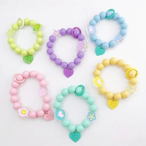 Close-up of six colorful macaron beaded bracelets with heart charms on white background