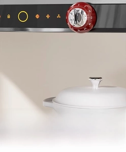 Macro shot of red mechanical kitchen timer with magnetic base attached to a metal surface