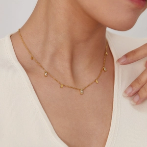Detail of gold necklace with rectangular zircon and metal bar pendants on model neck