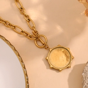 Detail of 18K gold-plated starburst pendant with chunky oval chain and toggle clasp