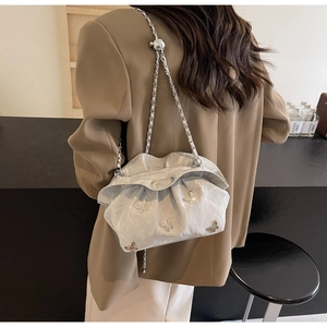Detail of silver pleated bucket bag with metal chain strap and butterfly charms