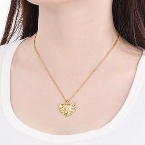 Close-up of gold leaf pendant necklace with textured surface and white pearl accents