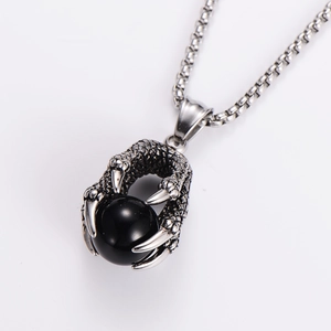 Detailed view of a silver dragon claw pendant holding a polished black bead on a box chain