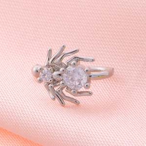 Macro shot of silver spider cuff with sparkling cubic zirconia on pink textured fabric