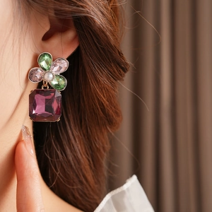 Macro shot of vintage floral earrings with colorful crystals and a purple square pendant