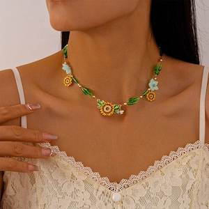 Detail of beaded necklace featuring sunflower pendant and green beads on model